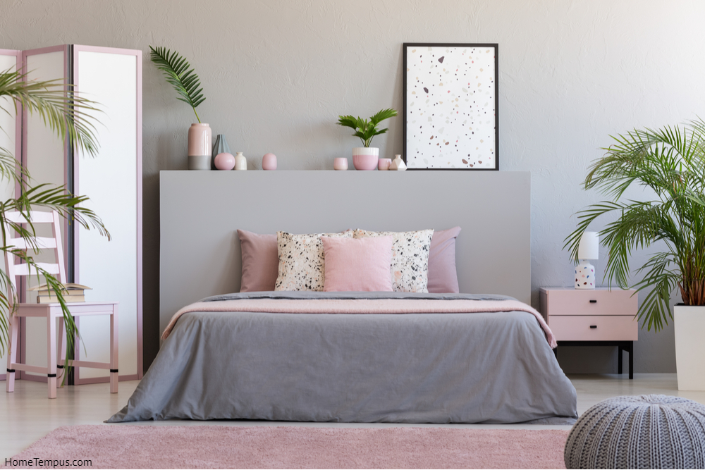 Poster on grey bedhead in bedroom interior with pink pillows on bed next to chair - Grey and Pink Bedboom Walls Colour Combination