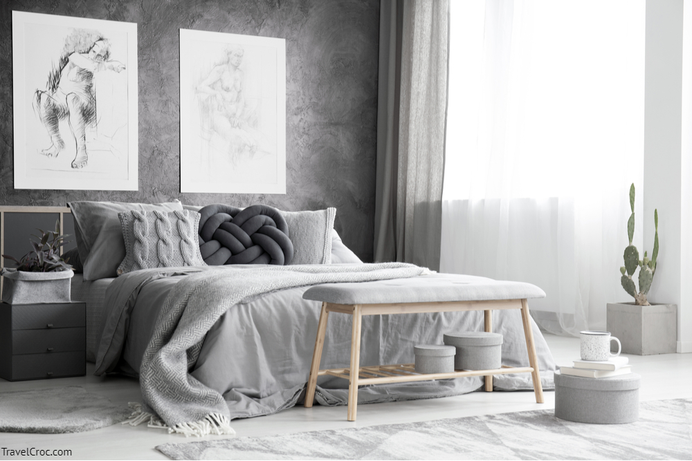 Grey colour combination for bedroom - Wooden bench and boxes in monochromatic bedroom interior with drawings on concrete wall above bed