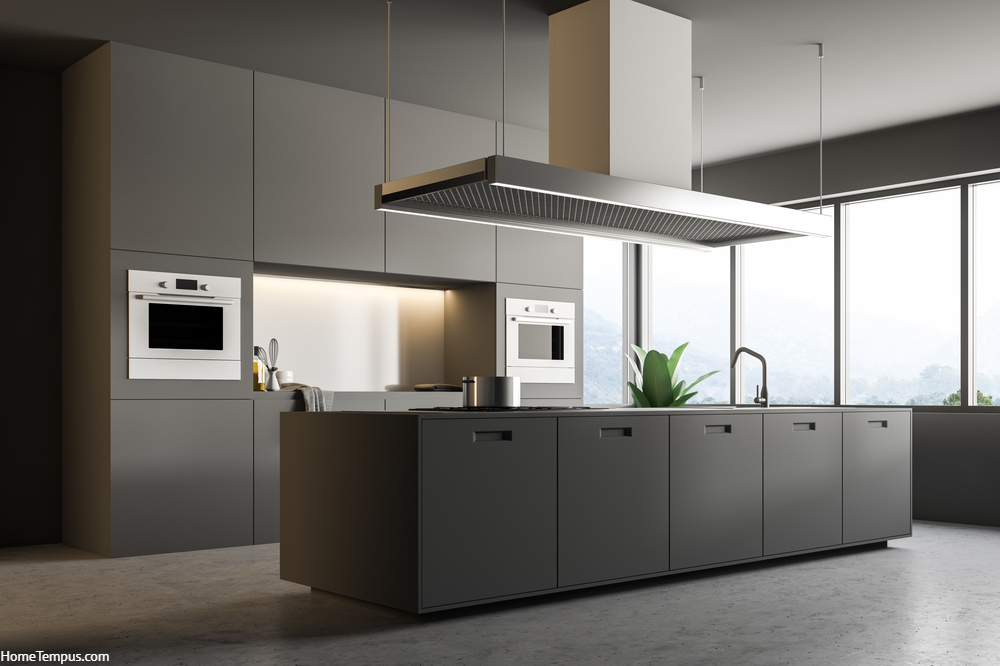 Interior of minimalistic kitchen with gray walls, concrete floor, gray countertops with built in appliances, and an island