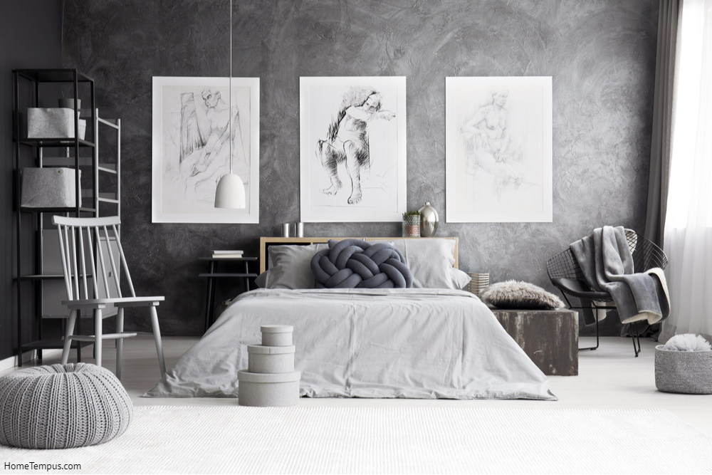 Pouf and boxes near grey chair in monochromatic bedroom with drawings on concrete wall above king-size bed - How to Pick Floors