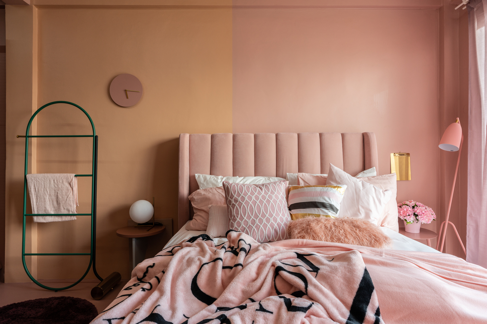 Pink and Burnt Orange Bedroom Studio with baby pink velvet fabric bed decorated byblanket, pillows, lamps