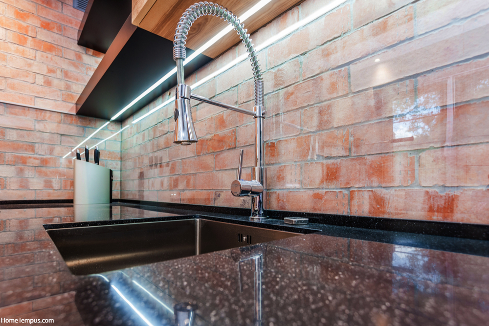 Modern kitchen with brick red walls. Sink and chrome faucet