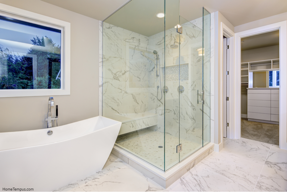 Sleek bathroom features freestanding bathtub atop marble floor - Glass shower enclosures