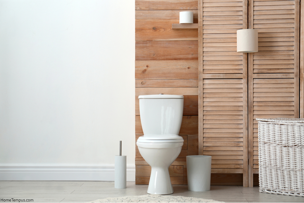 Toilet bowl near wooden wall in modern bathroom interior.